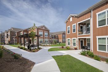 an exterior view of an apartment complex with walkways and grass  at Watermark on Twenty Mile, Parker